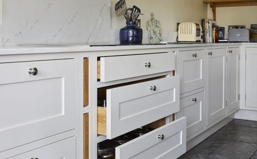 White kitchen cabinets with tiled flooring and quartz worktops. Landford Stone, Wiltshire.