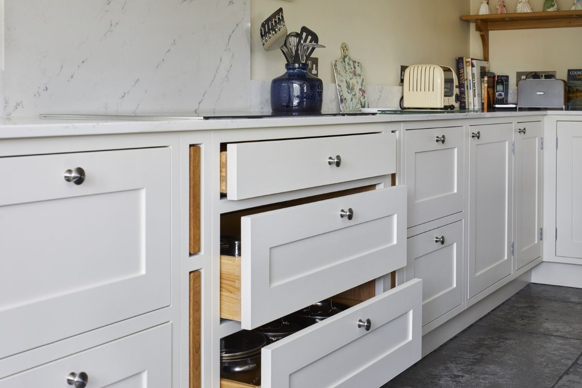 White kitchen cabinets with tiled flooring and quartz worktops. Landford Stone, Wiltshire.